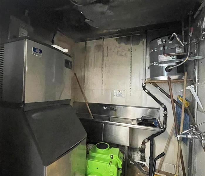 Fire aftermath shown as burnt shell of a utility room with blackened ceiling.